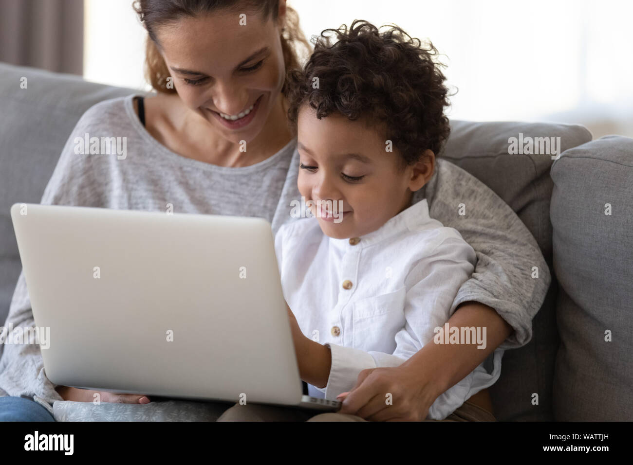 Felice madre abbracciare african carino kid figlio apprendimento utilizzando laptop Foto Stock
