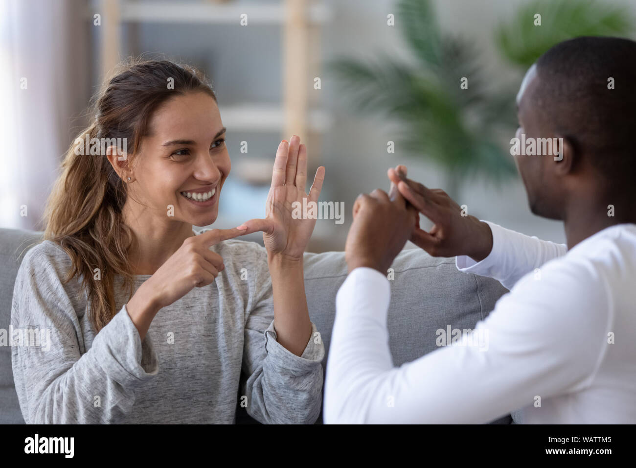 Sorridente etnia miste giovane parlando con il segno del dito lingua a mano Foto Stock