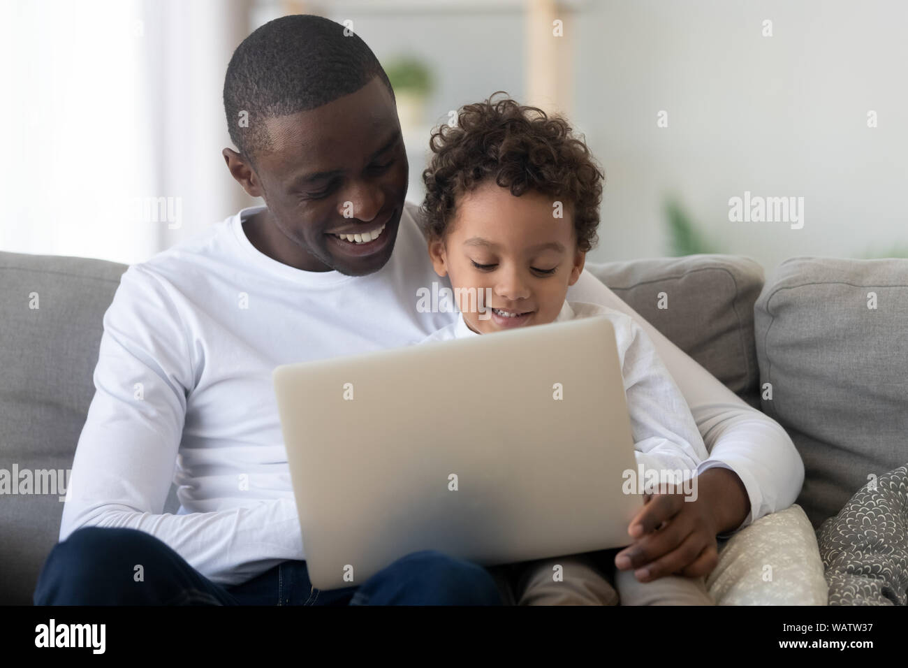 Carino kid figlio apprendimento utilizzando laptop con felice papà nero Foto Stock
