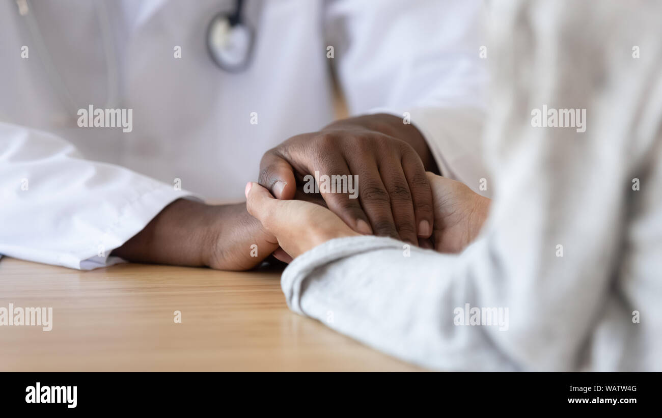 Grato paziente femmina tenendo le mani dell'Africano nero medico maschio Foto Stock