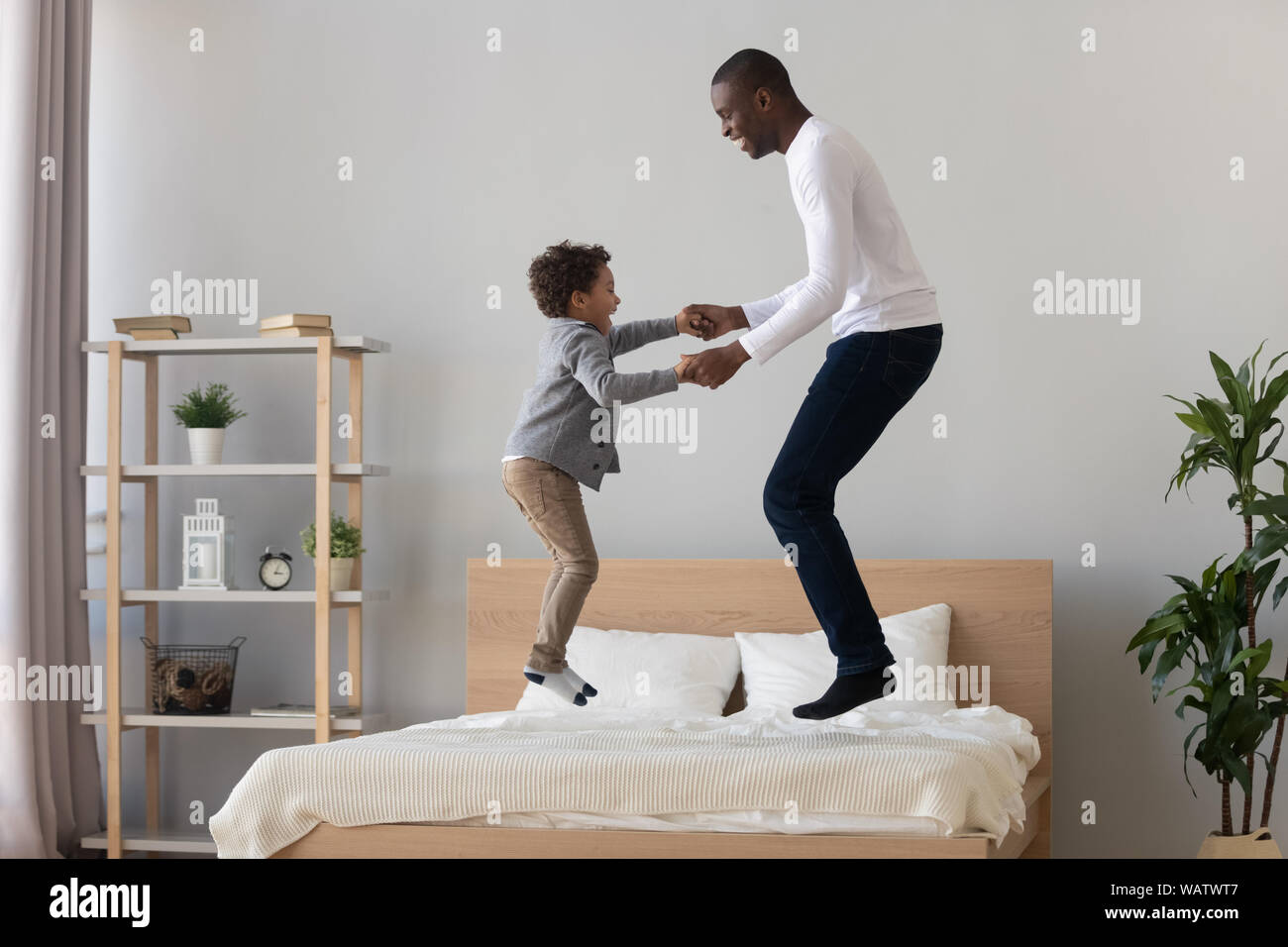 Felice padre nero e carino kid figlio di saltare sul letto Foto Stock