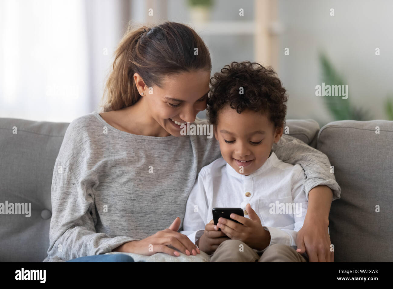 Felice etnia miste mom e carino kid figlio usando il telefono Foto Stock