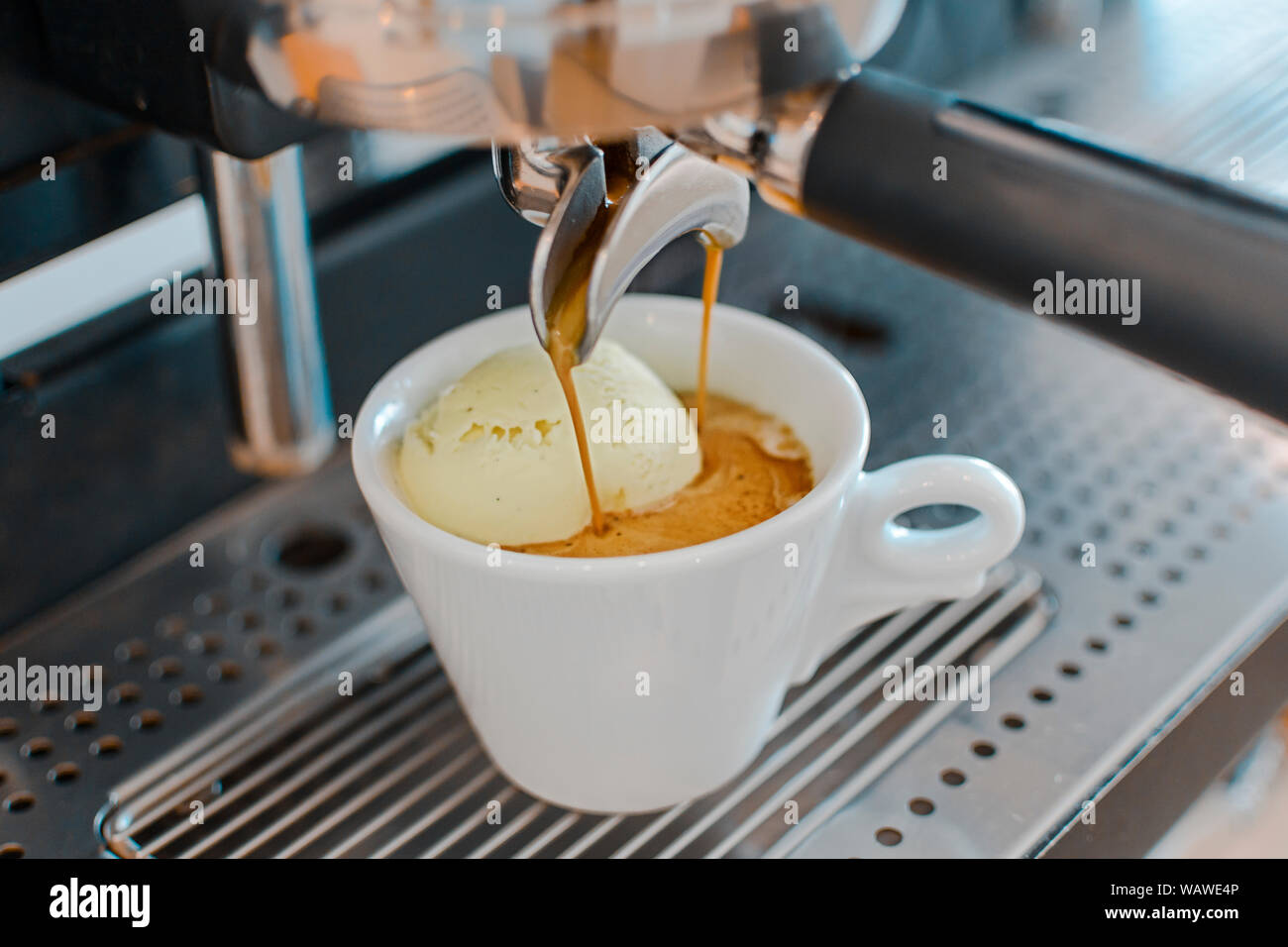 Affogato con caffè e gelati su una coppa in ceramica con il versamento di caffè dalla macchina per espresso Foto Stock