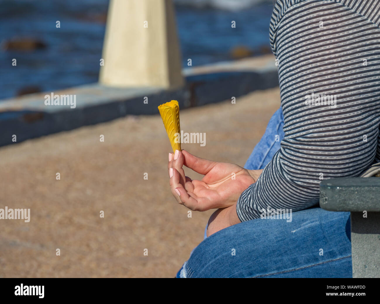 Donna seduta su una panchina sulla spianata di mangiare un gelato immagine in formato paesaggio con spazio di copia Foto Stock