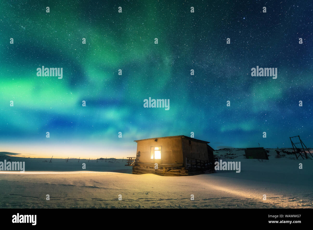 Aurora boreale sopra il vecchio piccola casa con luce gialla nella finestra Foto Stock