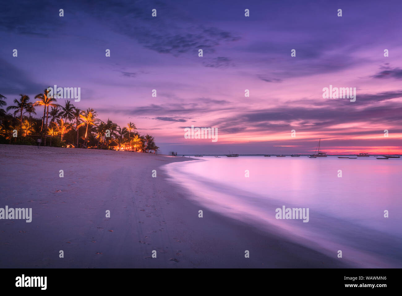 Spiaggia di sabbia con palme al tramonto colorato in estate Foto Stock