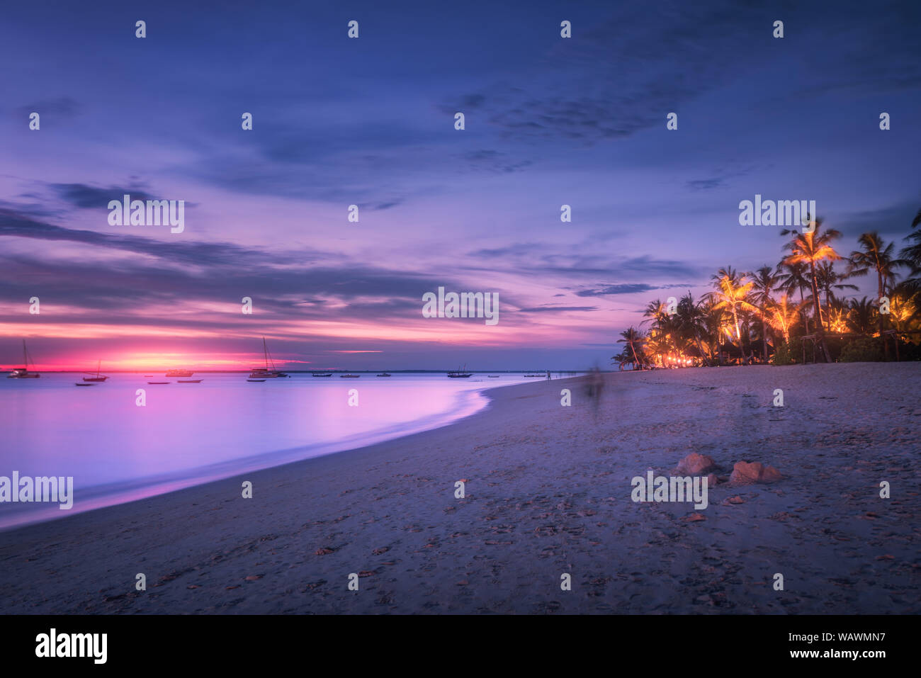 Spiaggia di sabbia con palme al tramonto colorato in estate Foto Stock