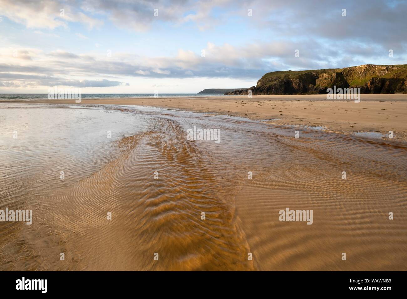 Flusso scorre verso il mare con la bassa marea su una spiaggia di sabbia, costa vicino Tolastadh, isola di Lewis, Scotland, Regno Unito Foto Stock