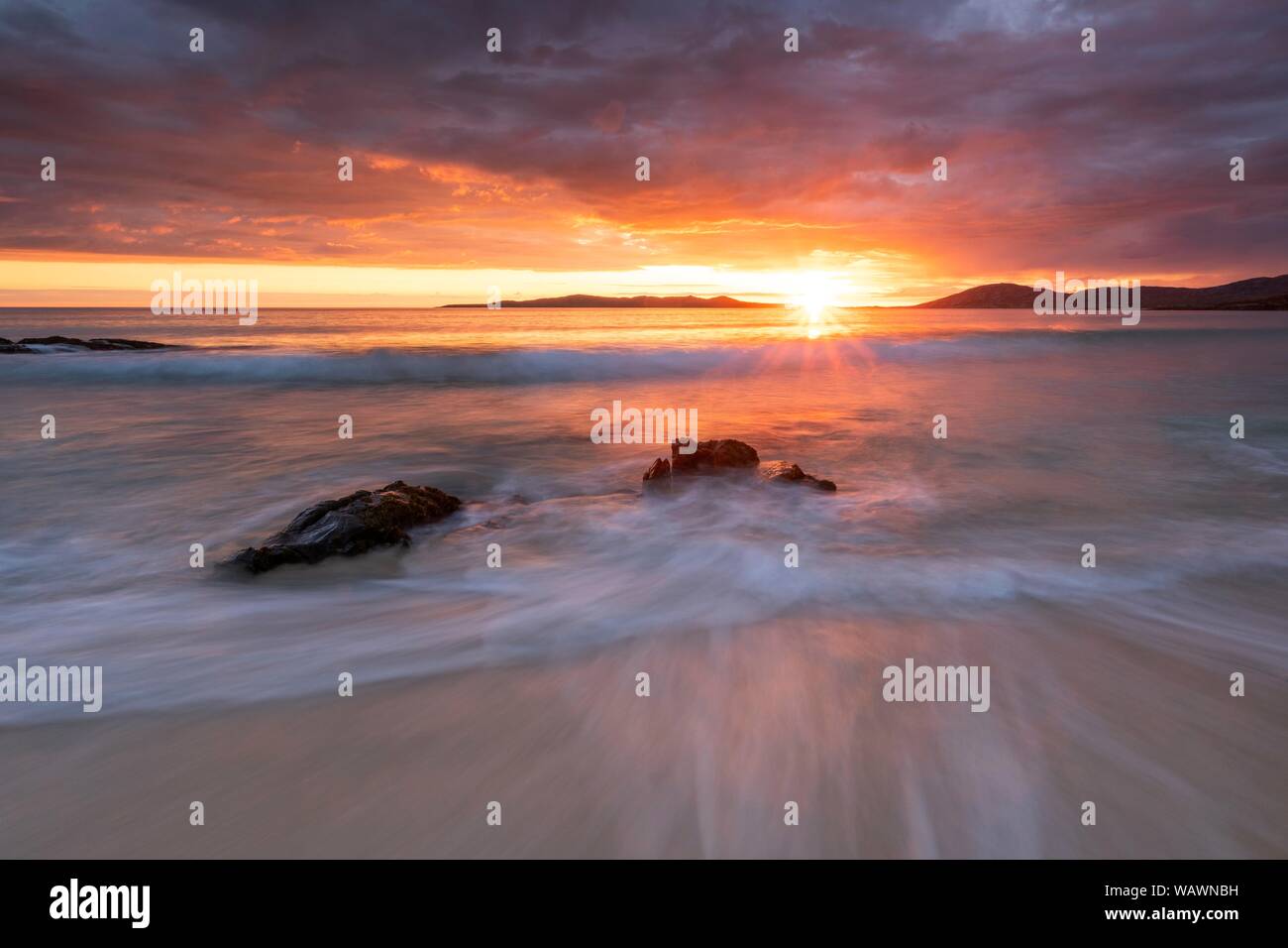 Rocce lavato mediante onde su una spiaggia di sabbia, drammatico tramonto con cielo nuvoloso sull'Oceano Atlantico, Isle of Harris, Scotland, Regno Unito Foto Stock