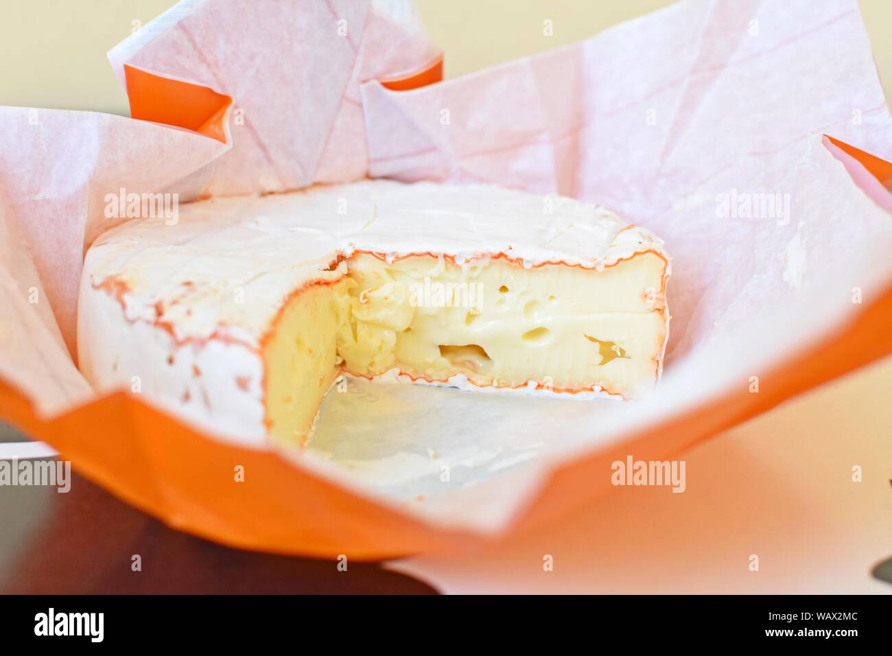 Vista laterale del formaggio Camembert nella confezione di carta originale aperta. Foto Stock