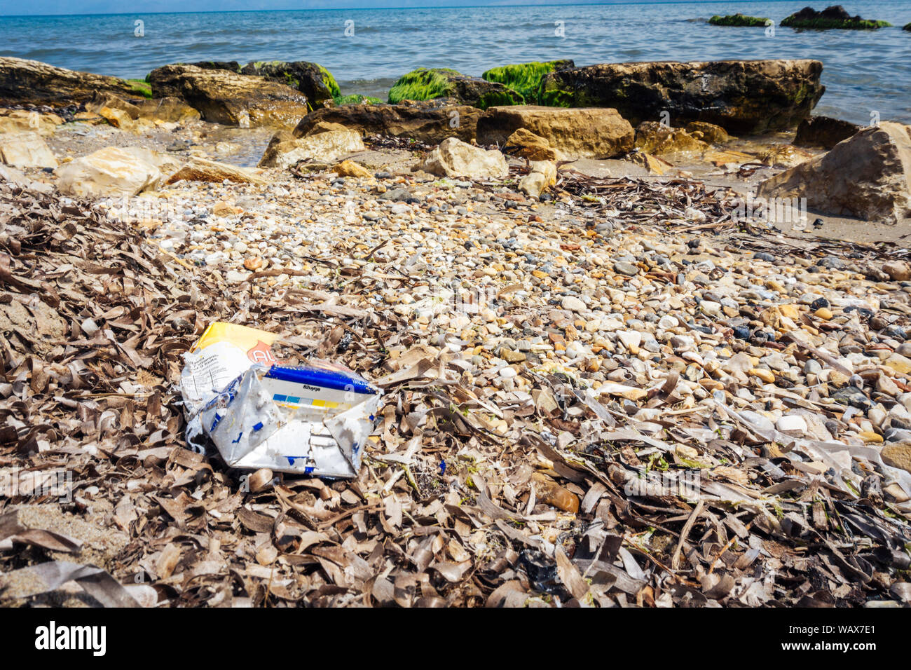 Involucro di plastica nella sabbia sulla spiaggia - di rifiuti di plastica in mare Foto Stock