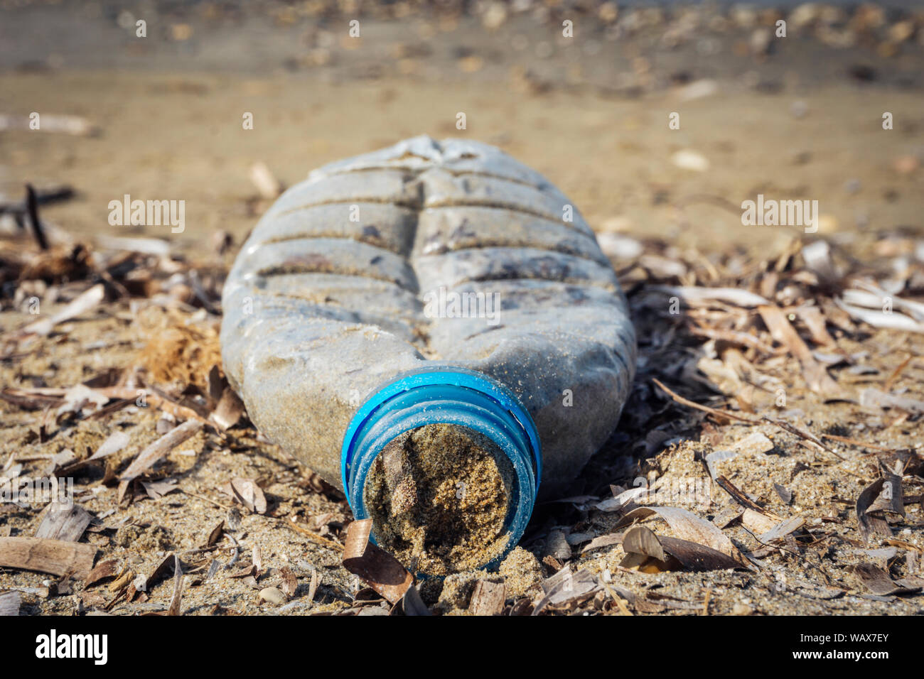 Ravvicinata di una bottiglia di plastica riempito di sabbia sulla spiaggia - di rifiuti di plastica in mare Foto Stock