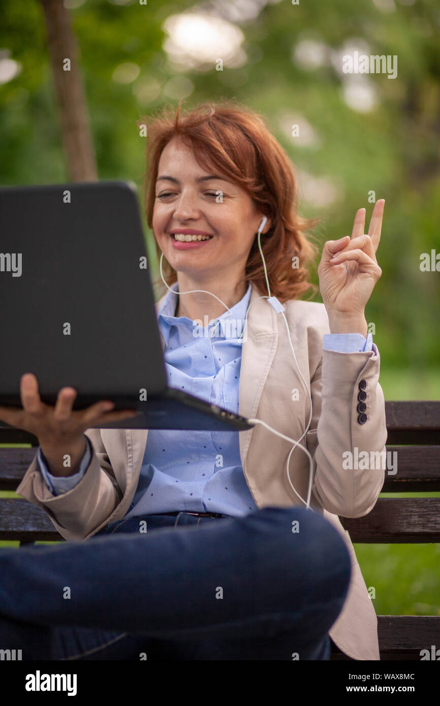 Una donna matura, gesti con le dita per un segno di pace, o in attesa di un momento di parlare. Foto Stock