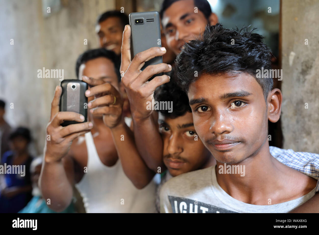 Un gruppo di giovani con cellulari nelle strade della vecchia Dacca, Bangladesh Foto Stock