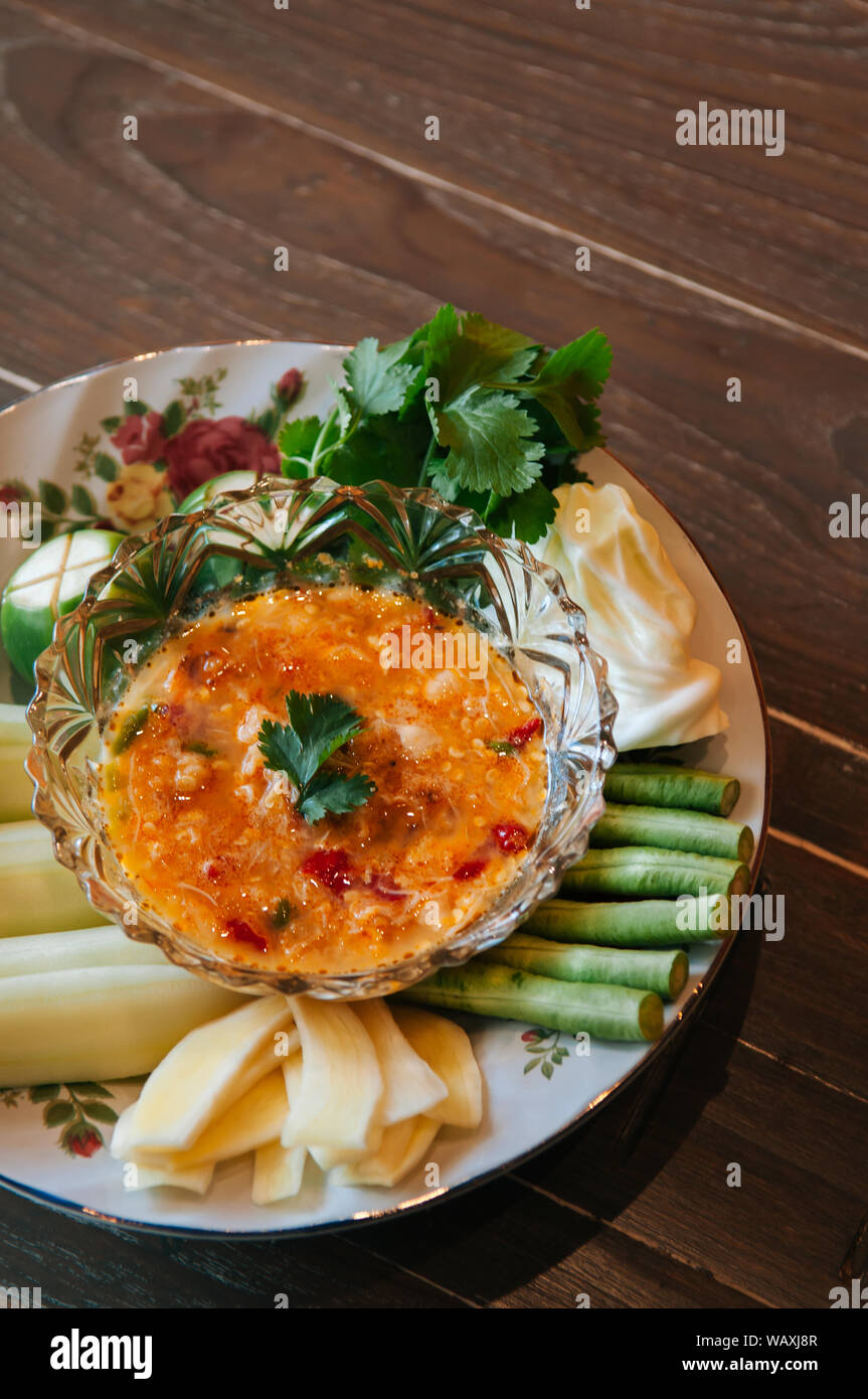 Cibo tailandese sul tavolo per la cena, Nam Prik Khai Poo - Chili di granchio salsa piccante in recipiente di vetro con vari tipi di verdura Foto Stock