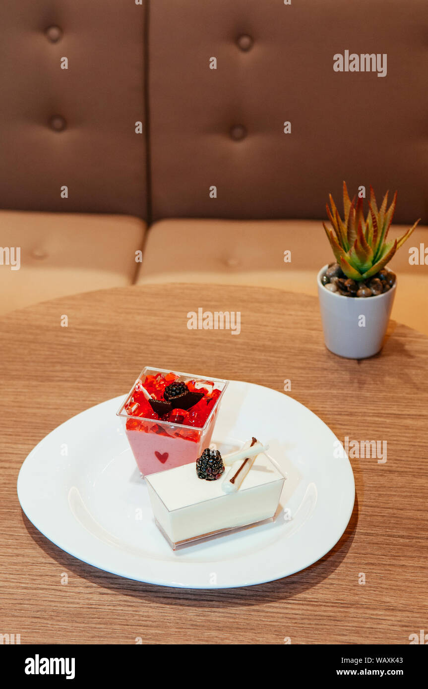 Fragole fresche e budino di latte con gelatina di fragola, il cioccolato, il cioccolato bianco e fresco blackberry su piastra bianca Foto Stock