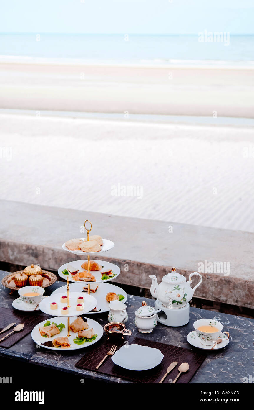 A lato della spiaggia il tè del pomeriggio con crostate e pasticceria dolci da forno sul colore scuro tavola di marmo in estate Foto Stock