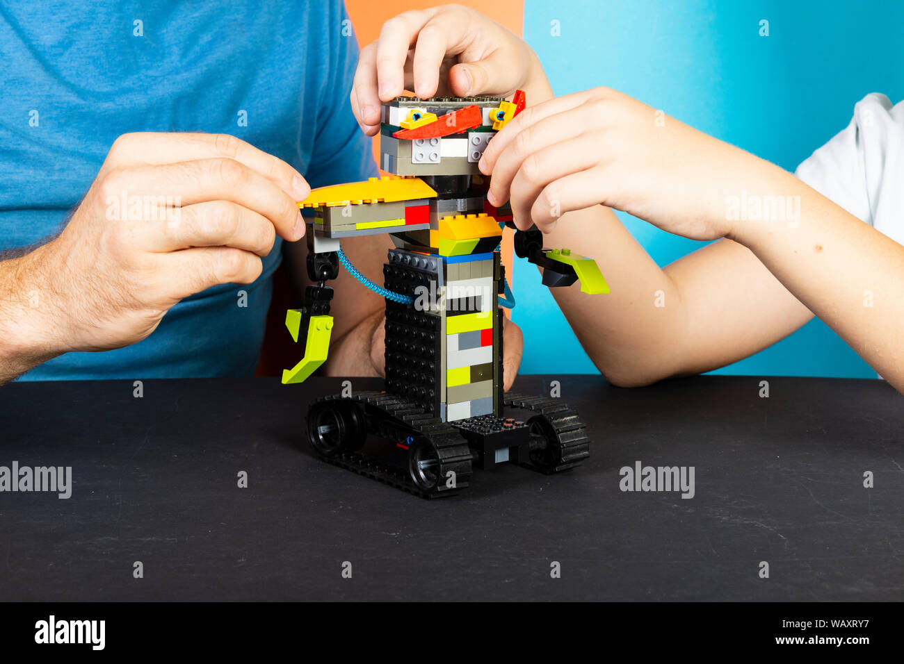 Un uomo e un ragazzo di assemblare da un costruttore di un robot. Maschio e i bambini con le mani in mano raccogliere lego Foto Stock
