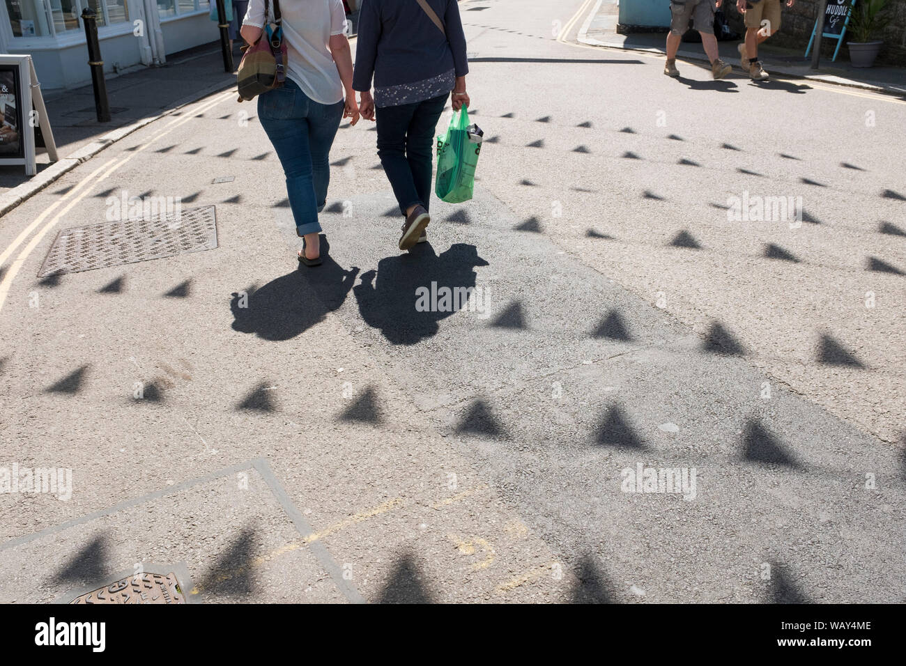 Due persone gettano ombre mentre lo shopping in Falmouth, Cornwall, Regno Unito Foto Stock