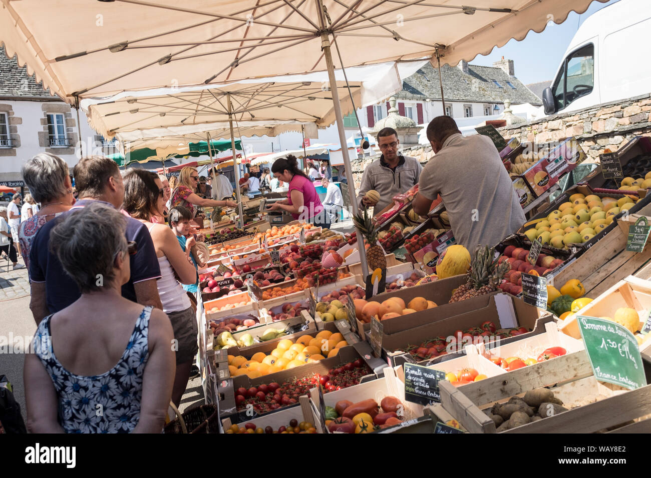 I clienti linea fino a comprare frutta fresca da uno stallo presso il settimanale mercato all'aperto in Plougasnou, Francia Foto Stock