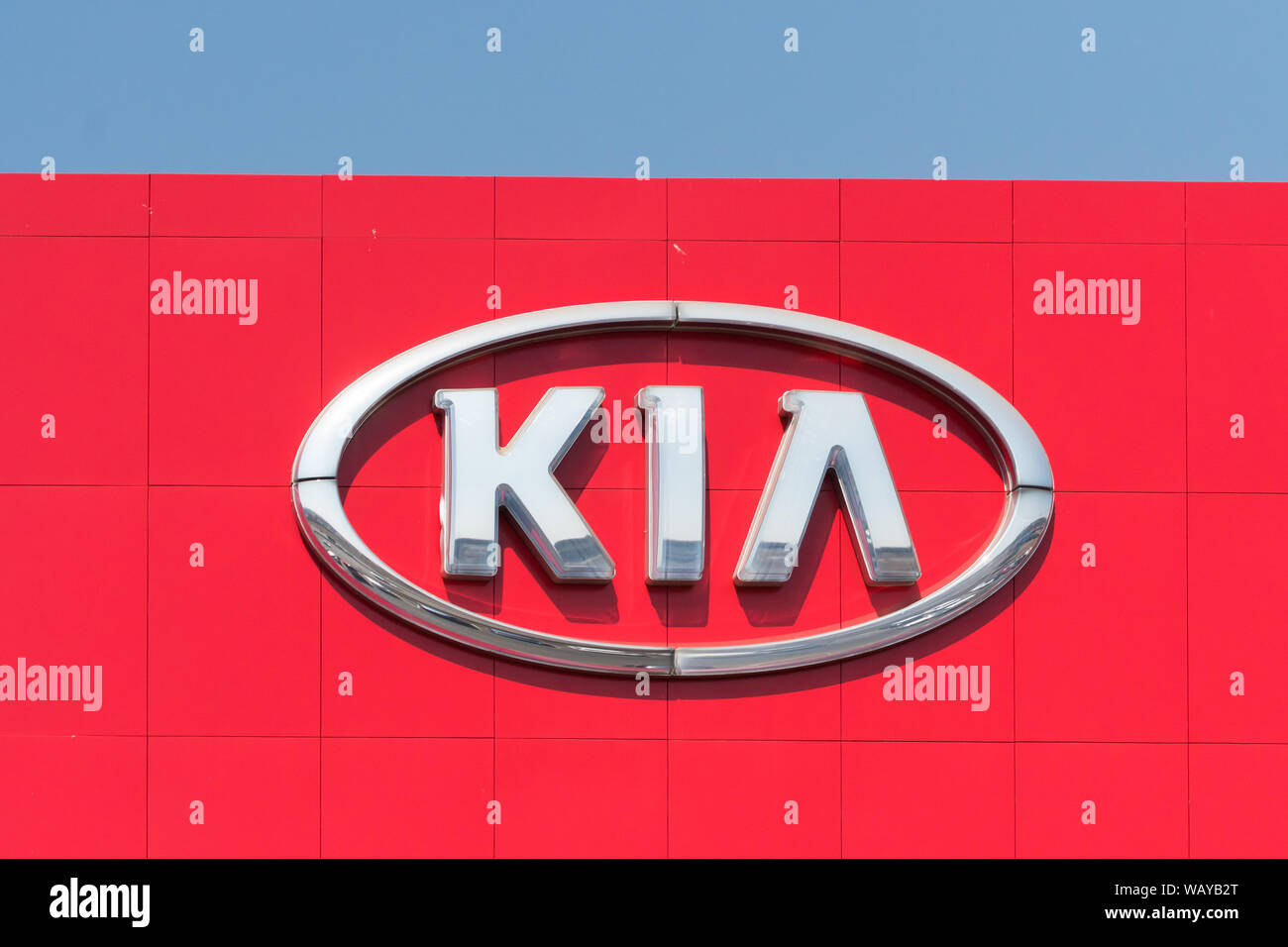 KIA argento o segno segnaletica logo emblema contro un colore rosso brillante facciata di un edificio a Johannesburg Gauteng, Sud Africa Foto Stock