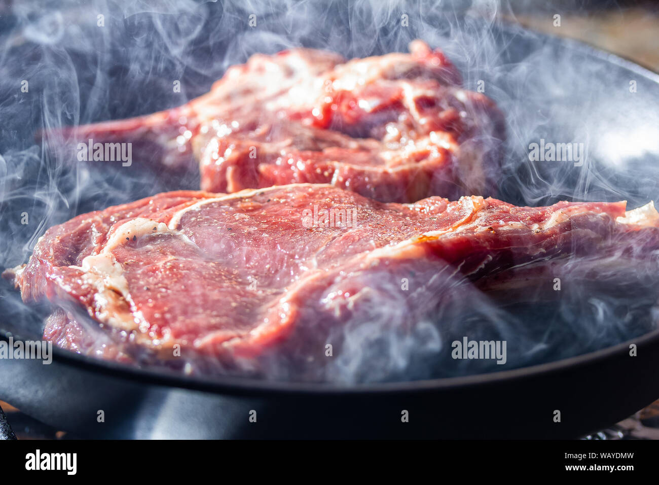 Fumo e vapore aumento da una bistecca beaf sul grill pan Foto Stock