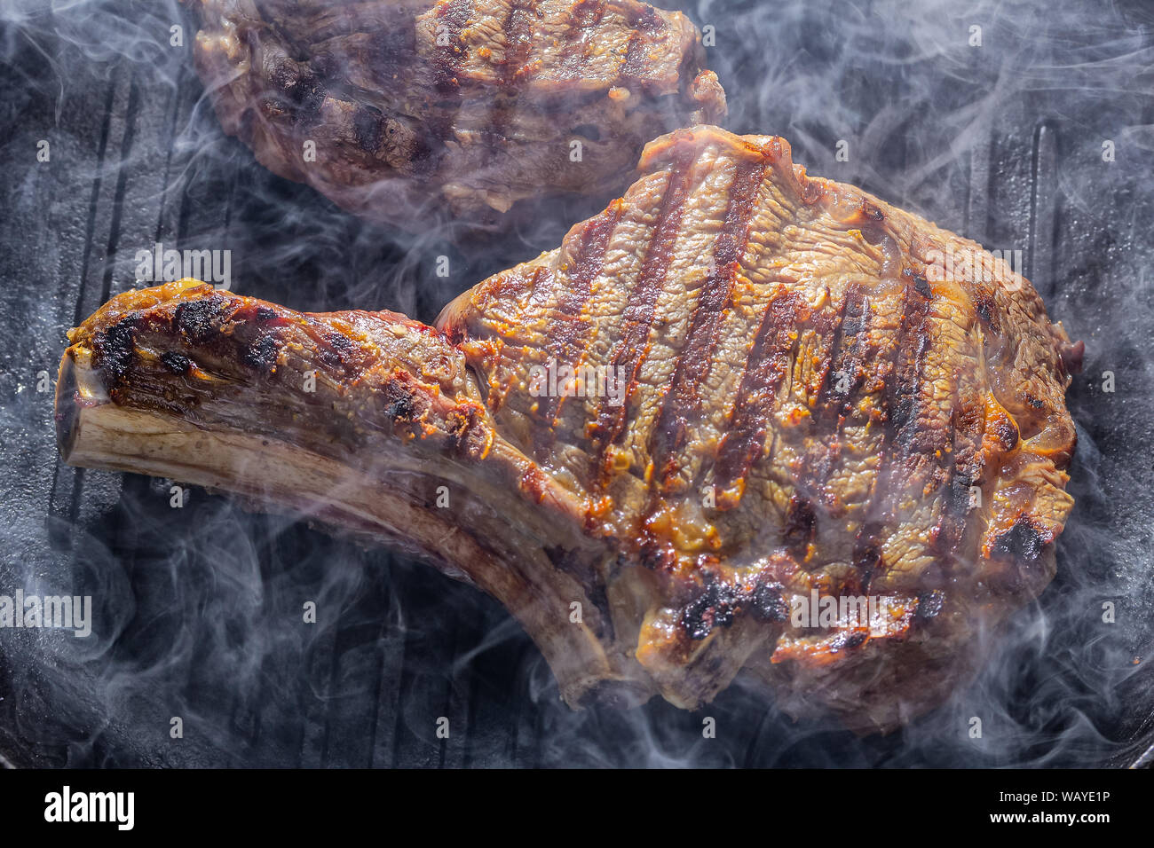 Fumo e vapore aumento da una bistecca beaf sul grill pan Foto Stock