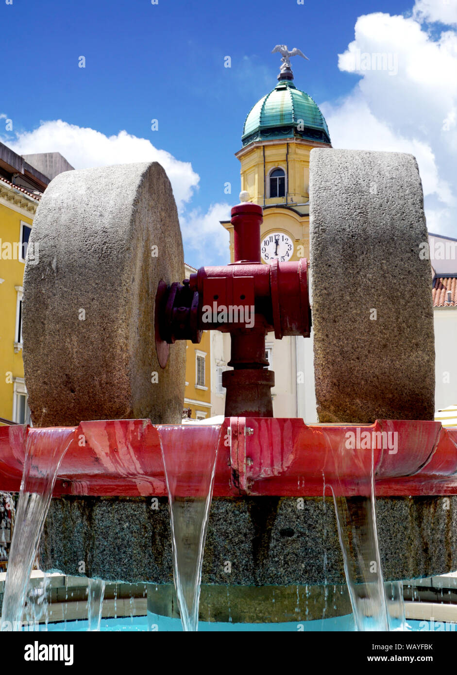 Macina in una fontana e un orologio di città su un monumento culturale in background. Patrimonio culturale e tradizionale della città croata di Rijeka Foto Stock