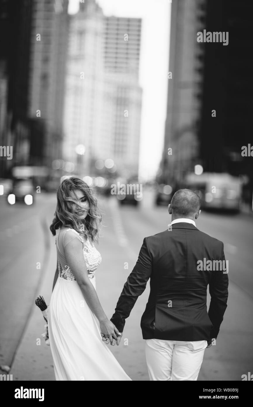 Bella sposa in un lungo abito bianco. Bello il suo fidanzato in una tuta blu. Matura in una grande città Foto Stock