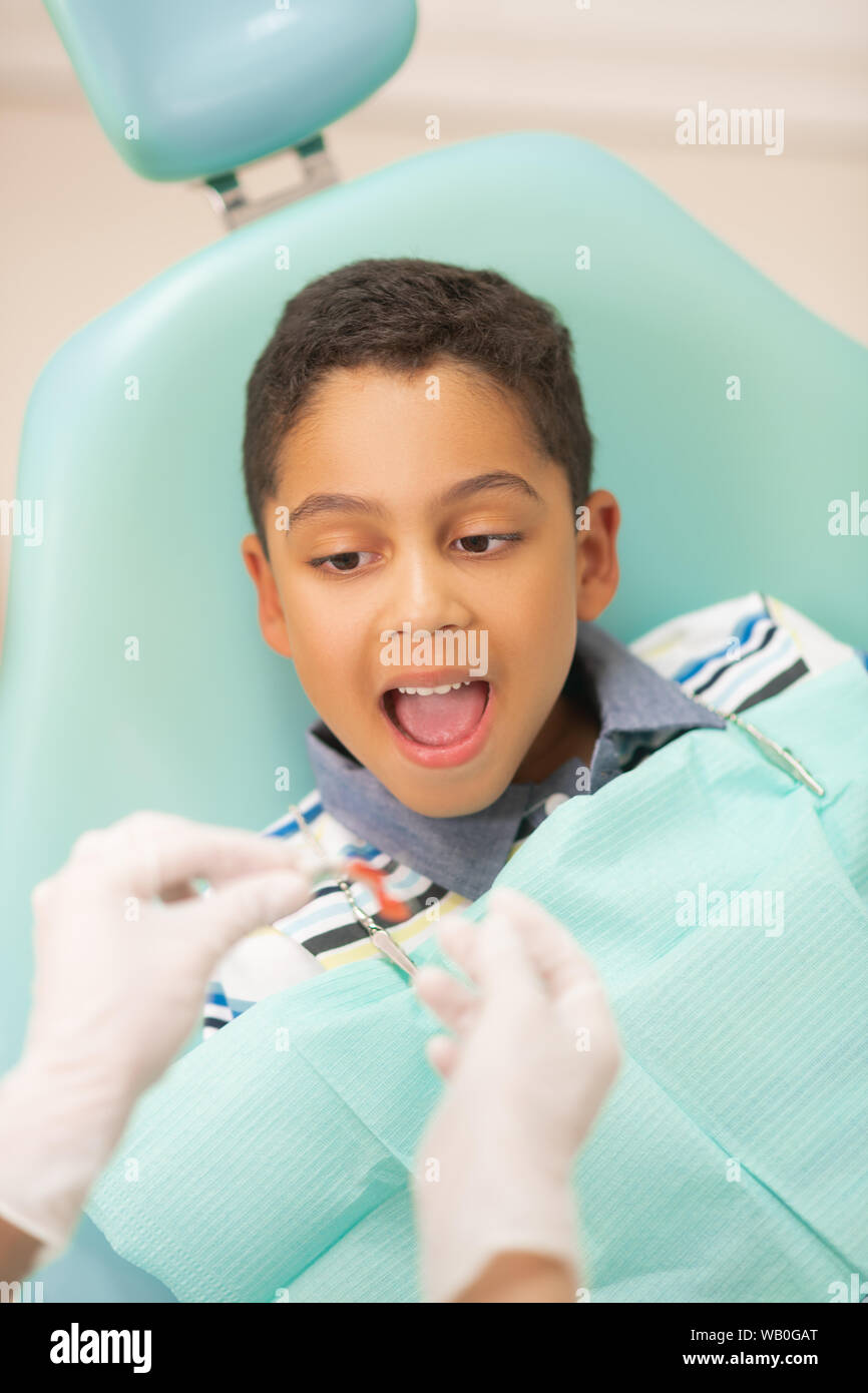 Ragazzo bocca di apertura mentre dentista mettendo protezione bocca Foto Stock