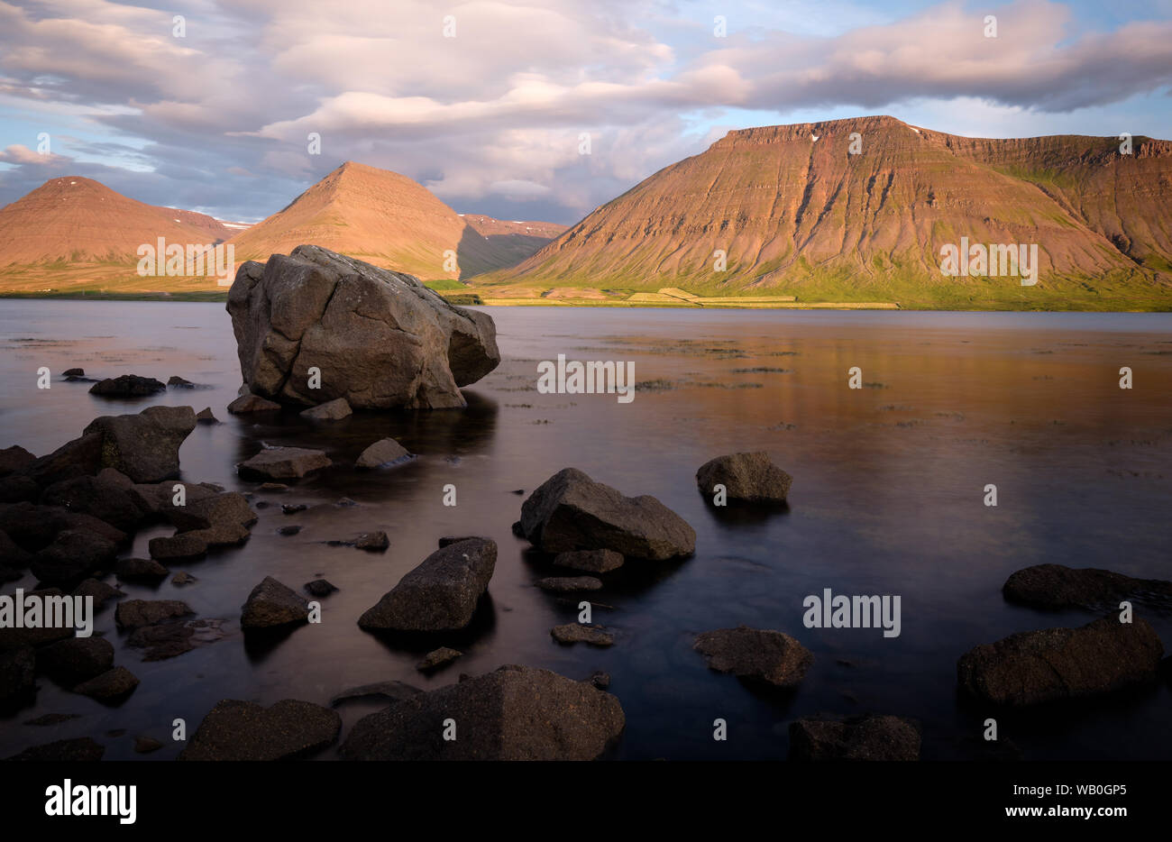 Estate tramonto a costa di Westfjords con possenti rocce in primo piano e belle montagne illuminato in background, Vestfirðir, Islanda Foto Stock