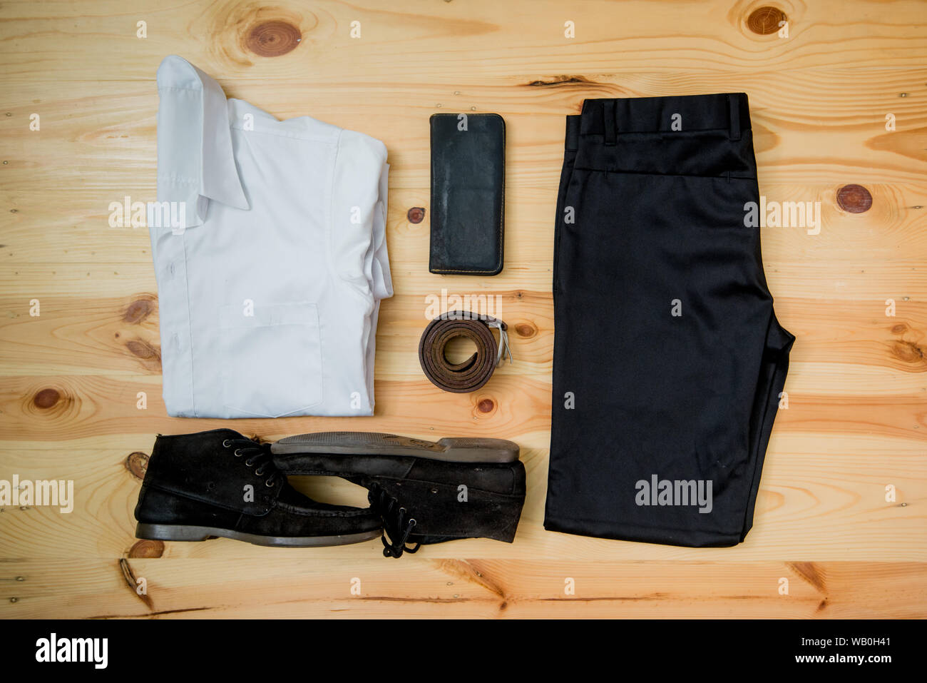 Uomo abiti casual accessori moda tavolo in legno, (t-shirt,jean,wallet,occhiali da sole,bicchieri,trasportatore,scarpe) Foto Stock