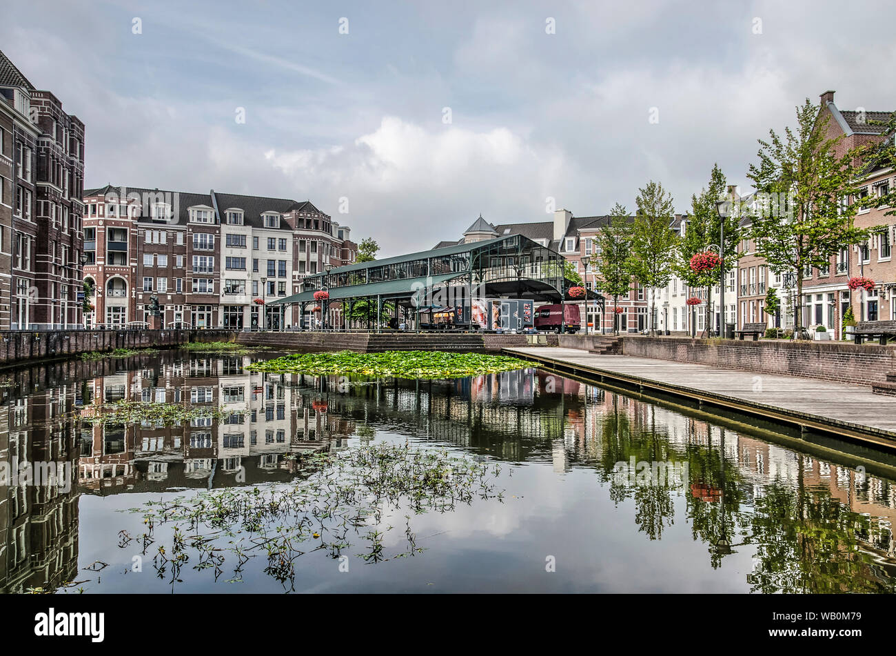 Helmond, Paesi Bassi, Agosto 16, 2019: neoclassicist case e market hall nel quartiere postmoderna Brandevoort riflettono nello stagno del cen Foto Stock