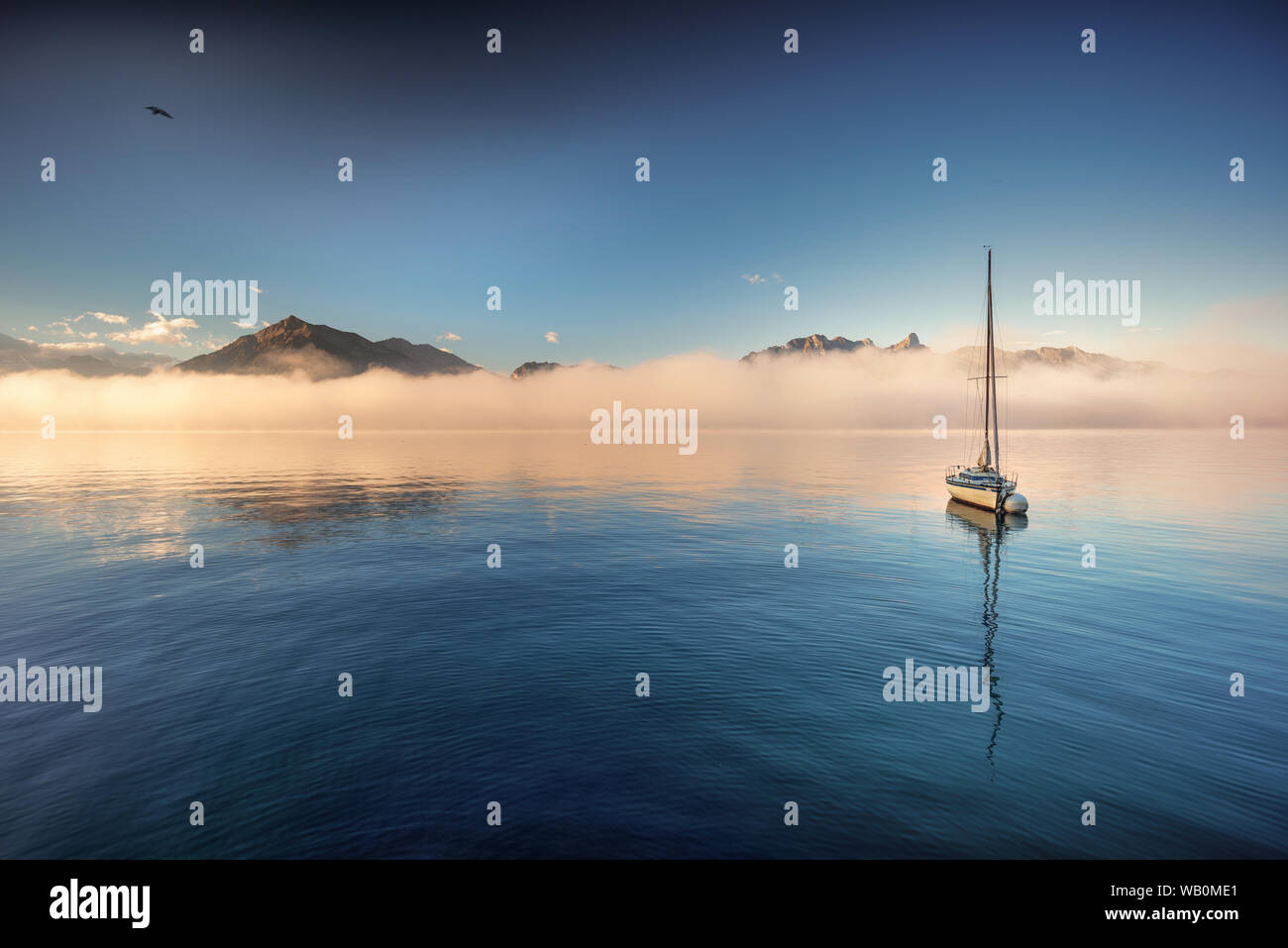 Niesen und Stockhorn torreggiante una mattina nebbia banca presso il lago di Thun con la barca a vela su una boa di ancoraggio riflettendo sulla superficie dell'acqua Foto Stock