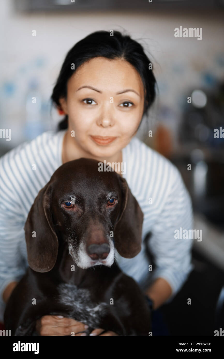 La donna in casa abbracciando il suo cane Foto Stock