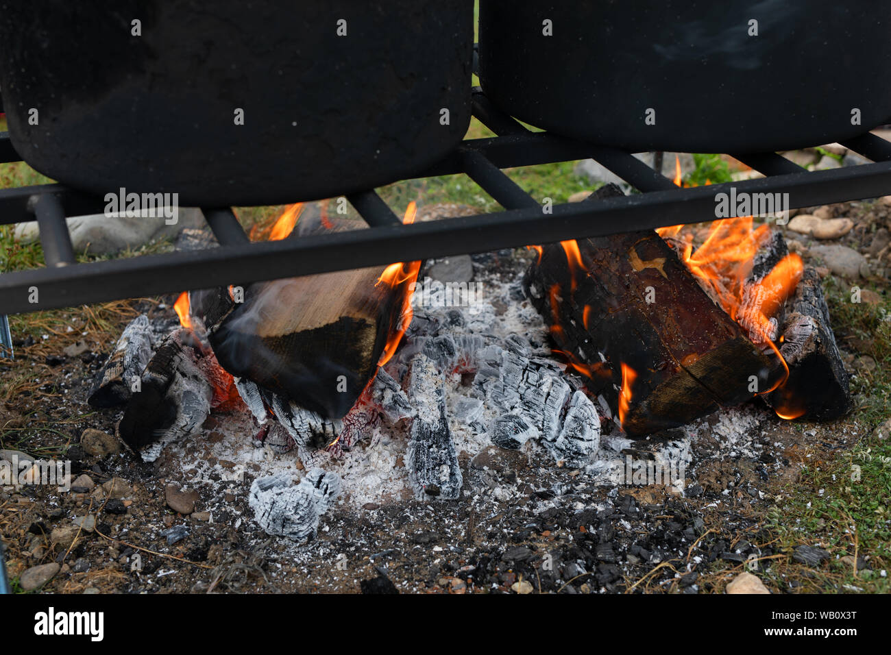 I log sono bruciore, un falò per la cottura. griglia superiore con pentole. campeggio cucina Foto Stock