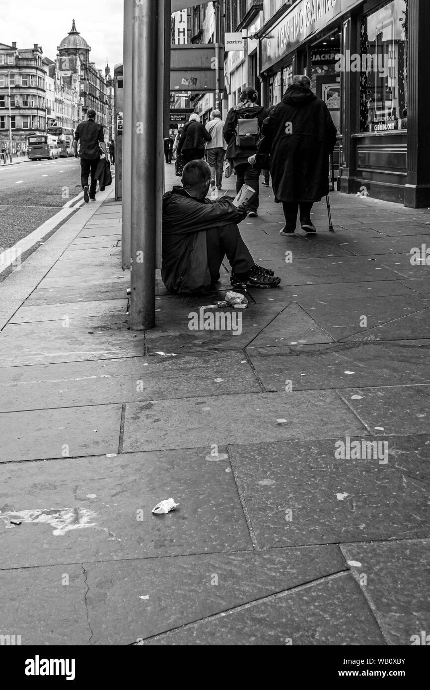 Glasgow, Scotland, Regno Unito - 22 Giugno 2019: le persone camminare davanti a un gentiluomo maschio ubicazione sul pavimento sporco con un McDonald's bicchiere di carta attraente per mon Foto Stock
