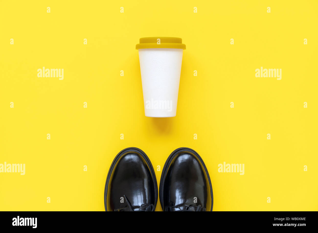 Stivali neri e una coppa di bambù con un coperchio di plastica per il caffè per andare Foto Stock