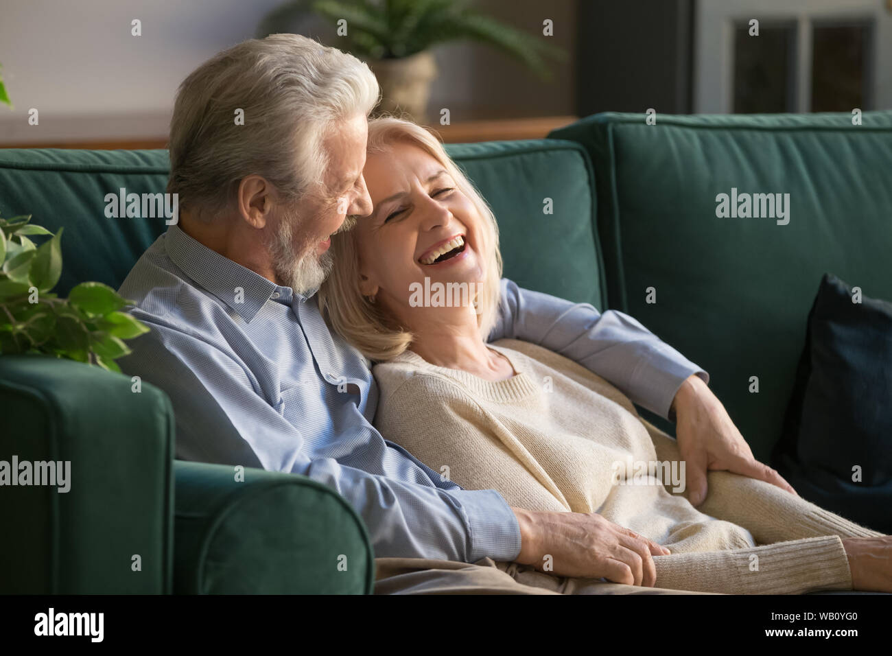 Felice senior vecchia coppia incollaggio abbracciando rilassante sedersi su un divano Foto Stock