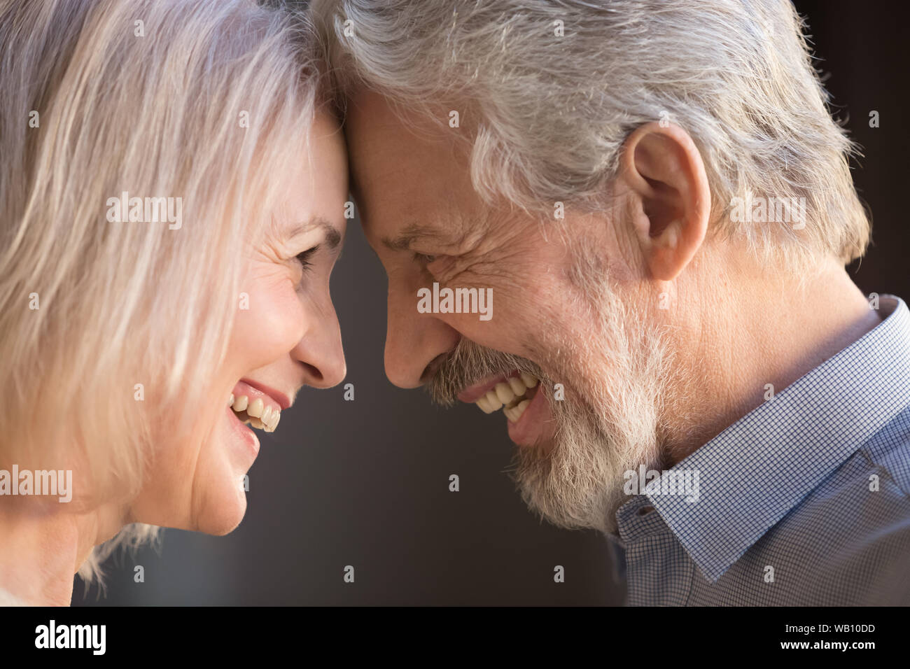 Felice vecchio paio di incollaggio di toccare fronte ridendo, closeup vista laterale Foto Stock