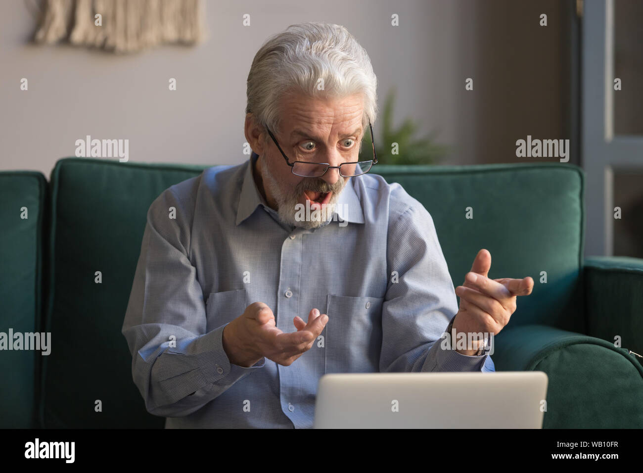 Scioccato senior uomo che guarda un notebook incredibile lettura online news Foto Stock