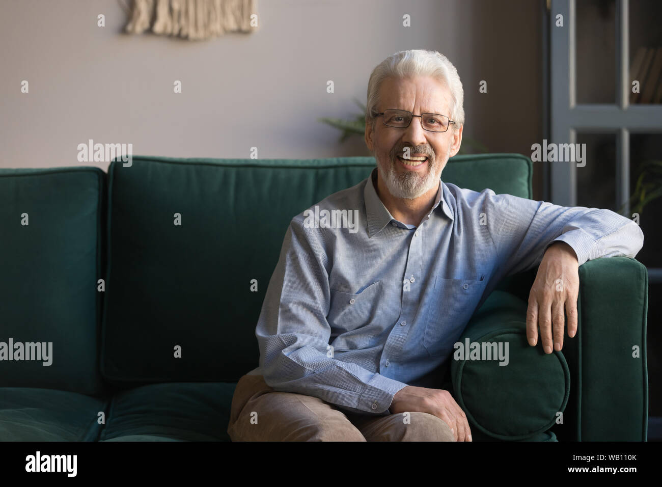 Senior sorridente uomo seduto sul divano nel soggiorno, ritratto Foto Stock