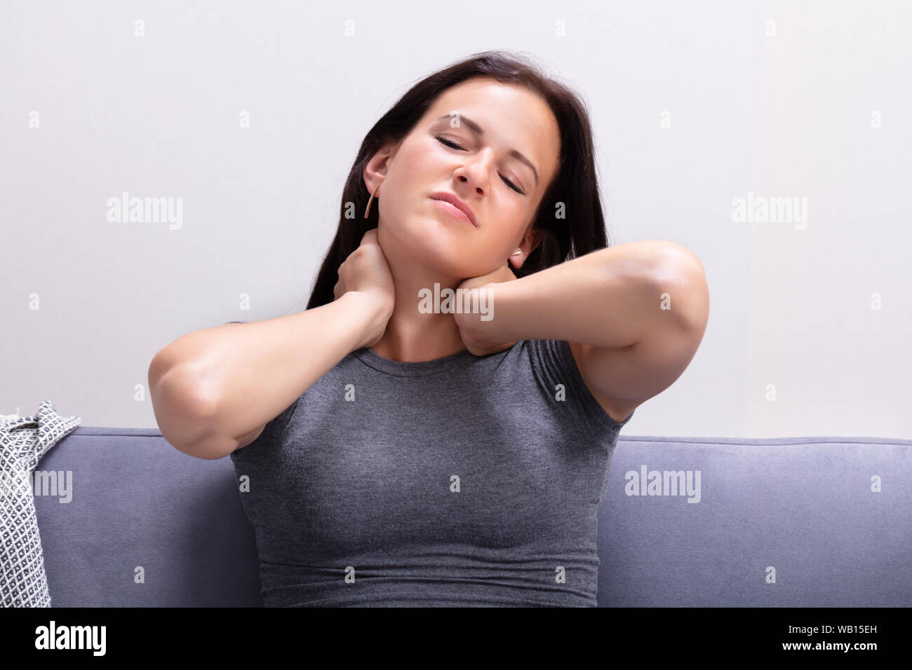 Ritratto di giovane donna che soffre di dolori al collo a casa Foto Stock
