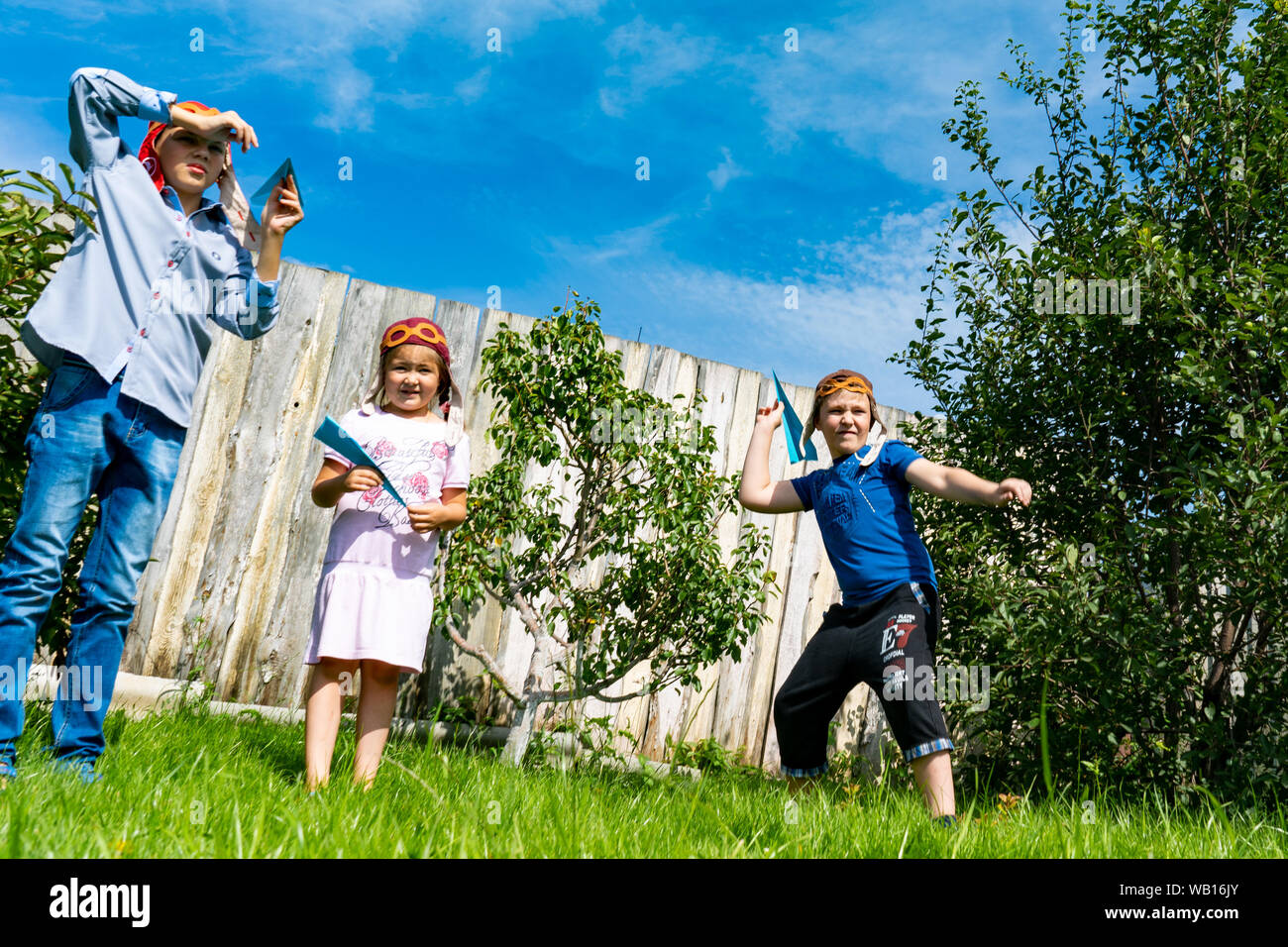 La regione di Celjabinsk, Russia - Agosto 2019.I bambini di differenti età giocare gli aeroplani di carta insieme. Ragazzi e una ragazza di decollo in cielo con il piano della carta Foto Stock