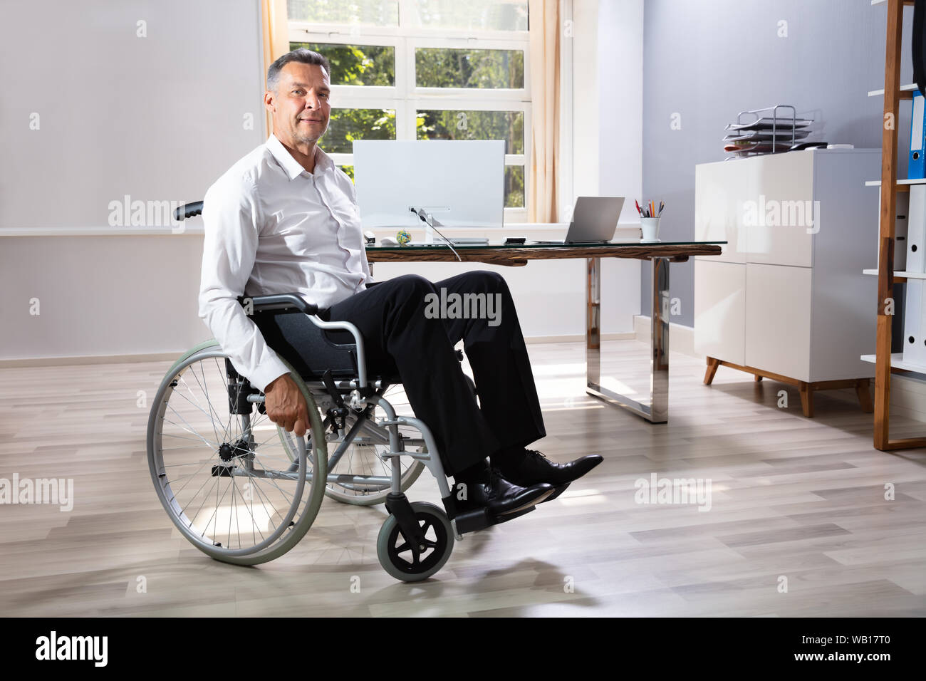 Imprenditore disabile seduto su una sedia a rotelle in Office Foto Stock