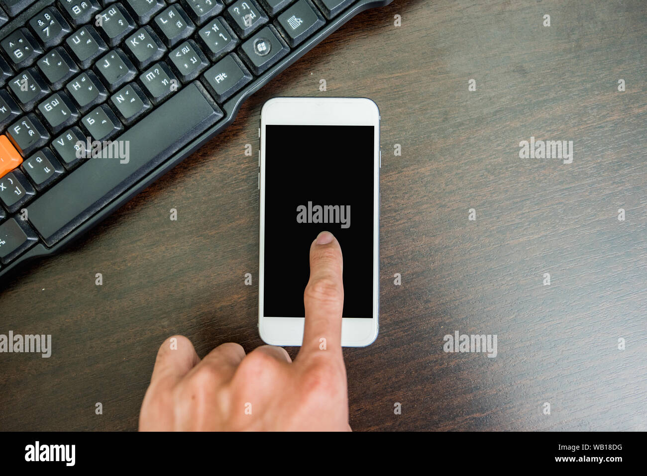 Mano utilizzando il telefono cellulare al computer Foto Stock