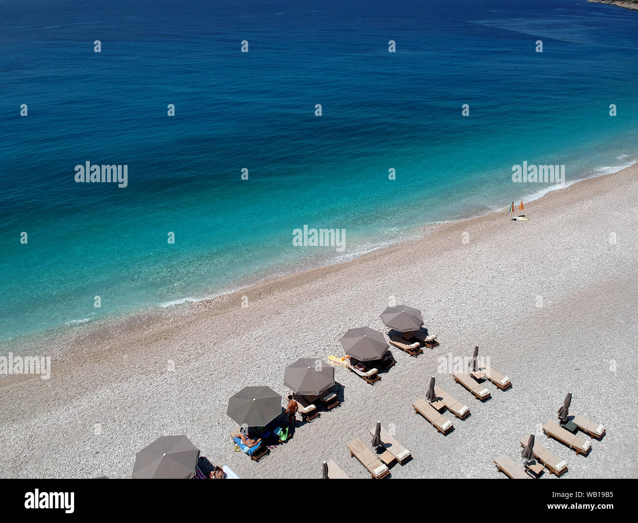 Vista aerea spiaggia rocciosa e crystal acque turchesi del Mar Ionio in Albania. Calma e rilassante vista in Palase spiaggia, ombrelloni e lettini Foto Stock