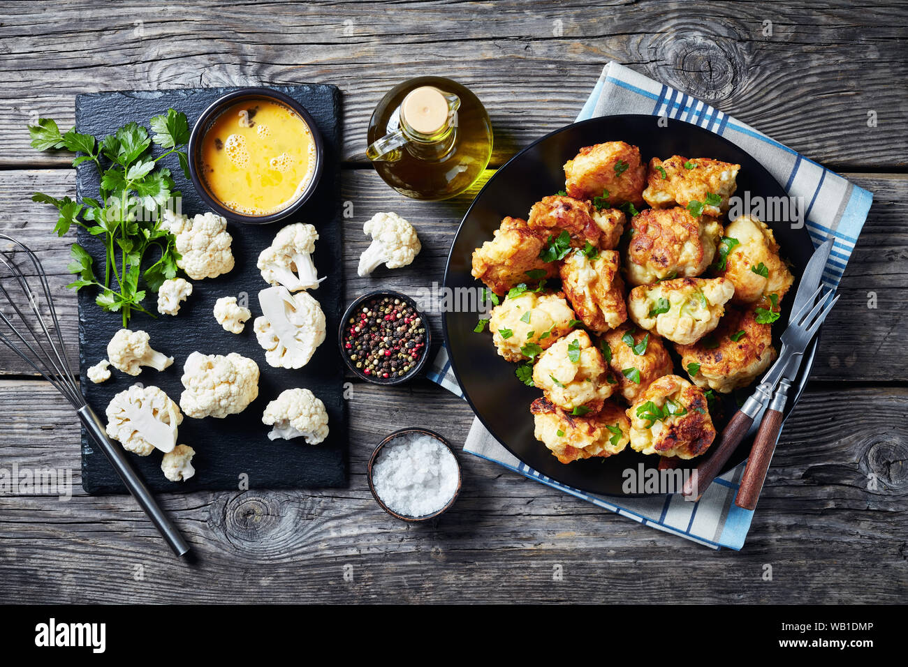 Tempura marocchino-style fritti cavolfiore servita su una piastra nera su un vecchio tavolo di legno con ingredienti su una scheda di ardesia, vista da sopra, cl Foto Stock