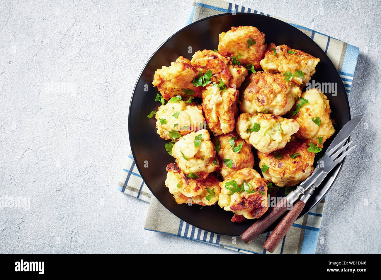 Tempura marocchino-style fritti cavolfiore servita su una piastra nera su una tavola di cemento, vista da sopra, close-up, flatlay, spazio vuoto Foto Stock
