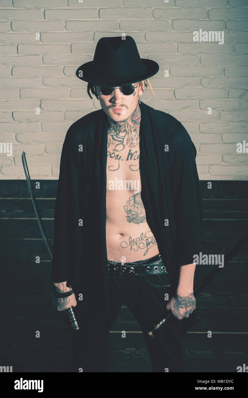 Harakiri, suicidio rituale. Onore e dignità. Guerriero in black hat e  aprire i vestiti che mostra tatuato torso. L uomo con la spada in piedi sul  pavimento di legno Foto stock -